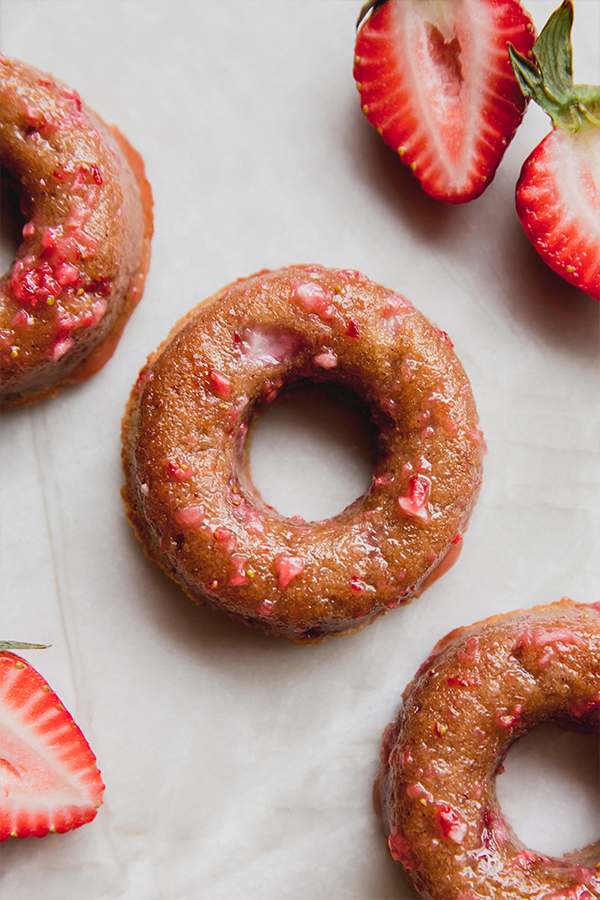 A few strawberry mini donuts with cut up strawberries.