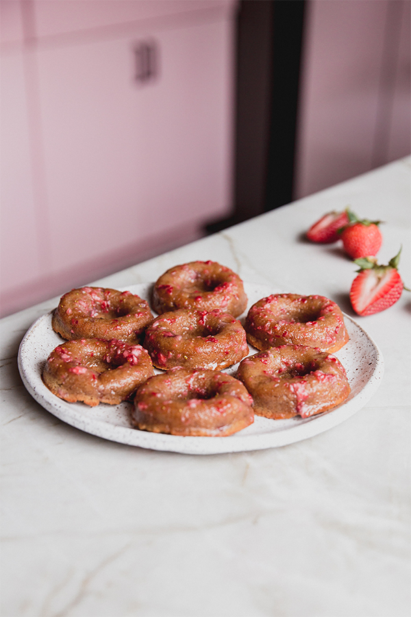 A plate full of strawberry mini donuts sitting on the counter.