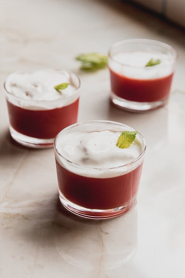 Three cups of sicilian watermelon puddings on a counter.