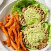 Avocado chicken burgers topped with avocado spread with a side of sweet potato fries.