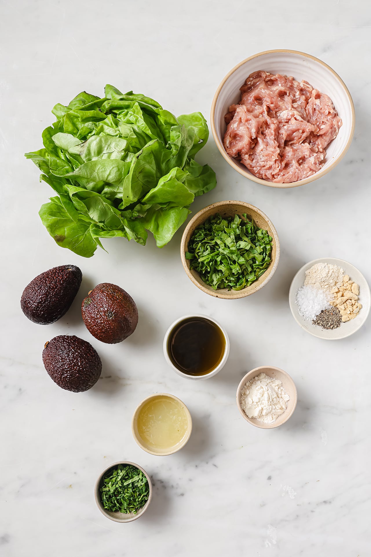 Spinach avocado chicken burger ingredients on a marble table. 