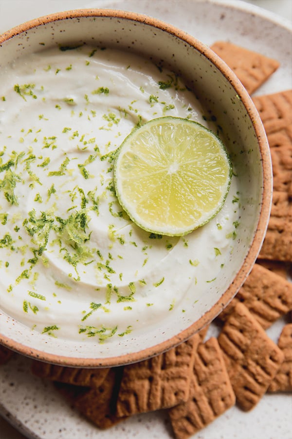 A bowl of key lime pie dip with graham crackers for dipping.