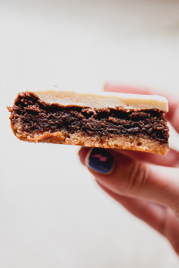 A s'mores brownie being held in a hand where you can see the layers.