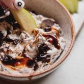 snickers salad dip in a bowl with a green apple slice dipping in