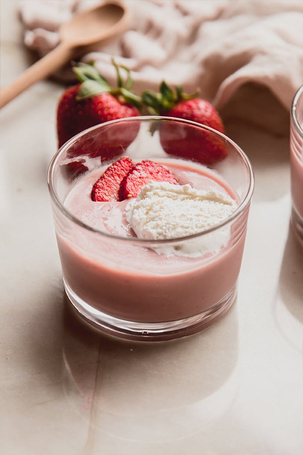 A cup of strawberries and cream pudding on the counter.