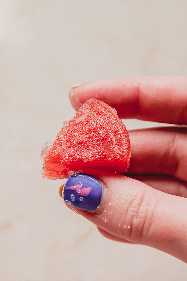 A sour patch copycat watermelon gummy being held in a hand.