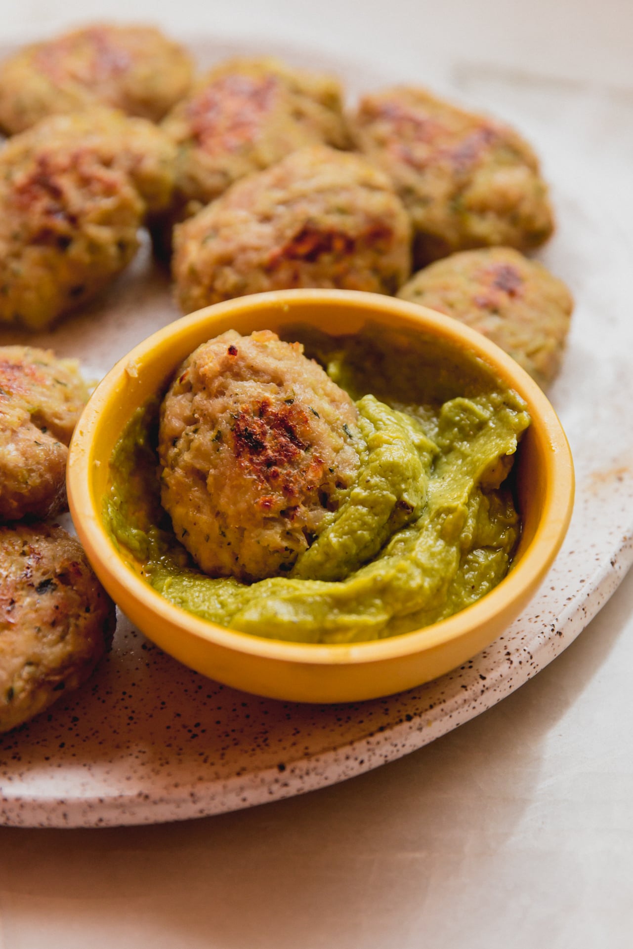 A plate with zucchini chicken nuggets and dipping sauce.