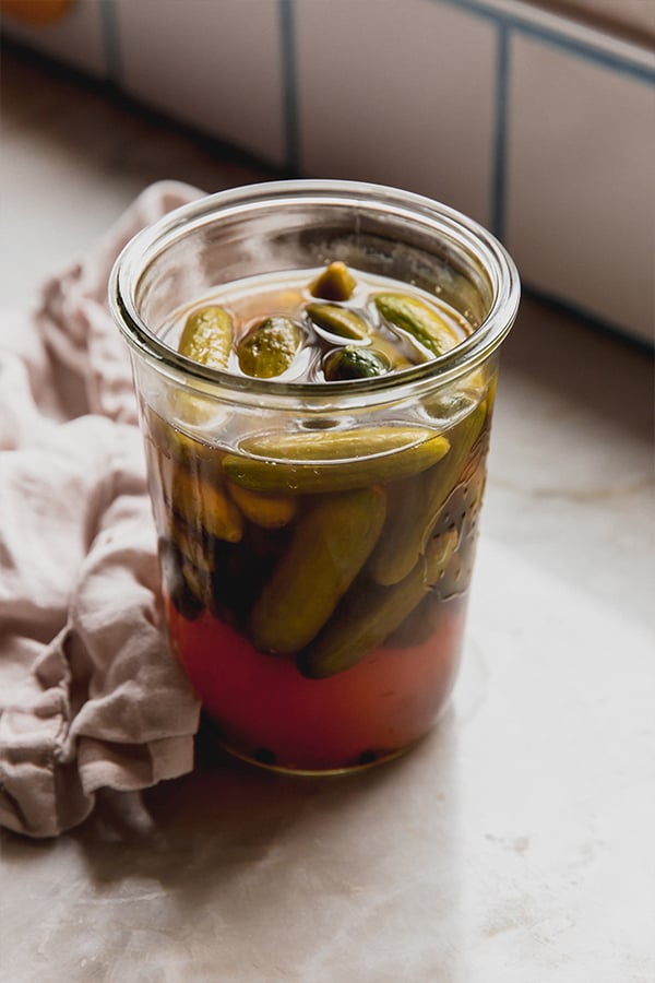 A jar of apple cider vinegar pickles sitting on the counter ready to be enjoyed.