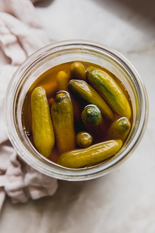 A jar of apple cider vinegar pickles sitting on the counter.