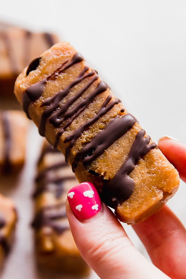 A cookie dough protein bar being held in a hand.