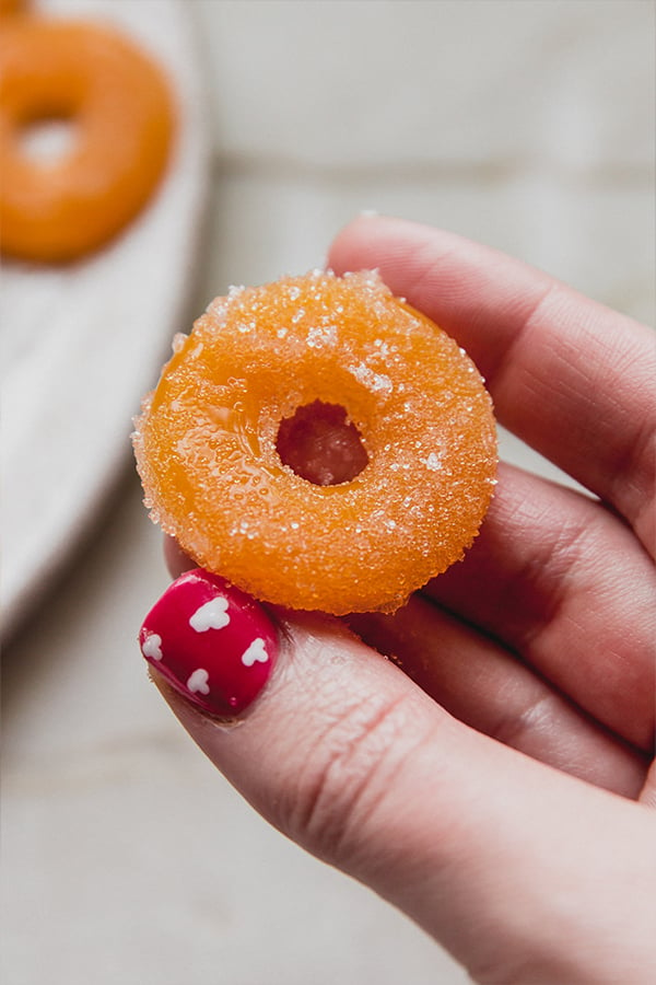 A peach ring gummy being held in a hand.