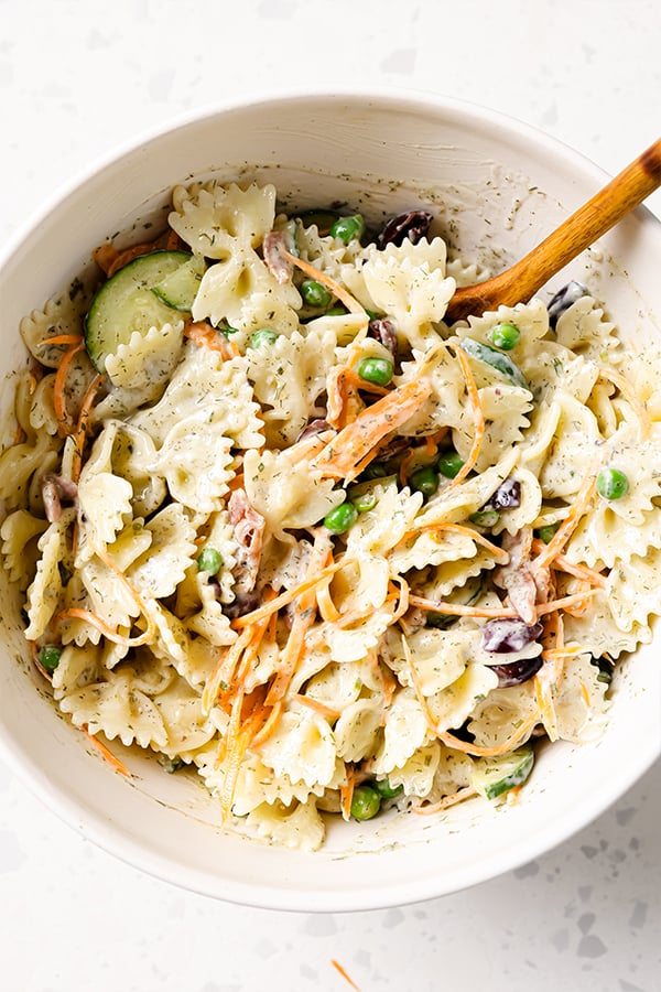 A mixing bowl filled with bacon ranch bow-tie pasta salad ready to be enjoyed.