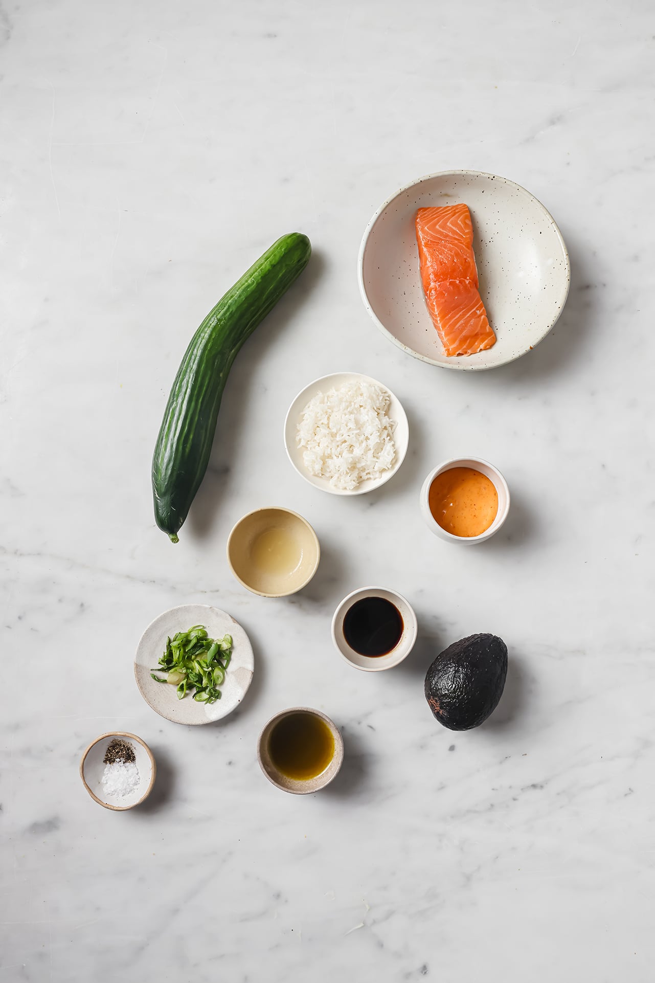 Salmon cucumber avocado boat ingredients on a marble table.