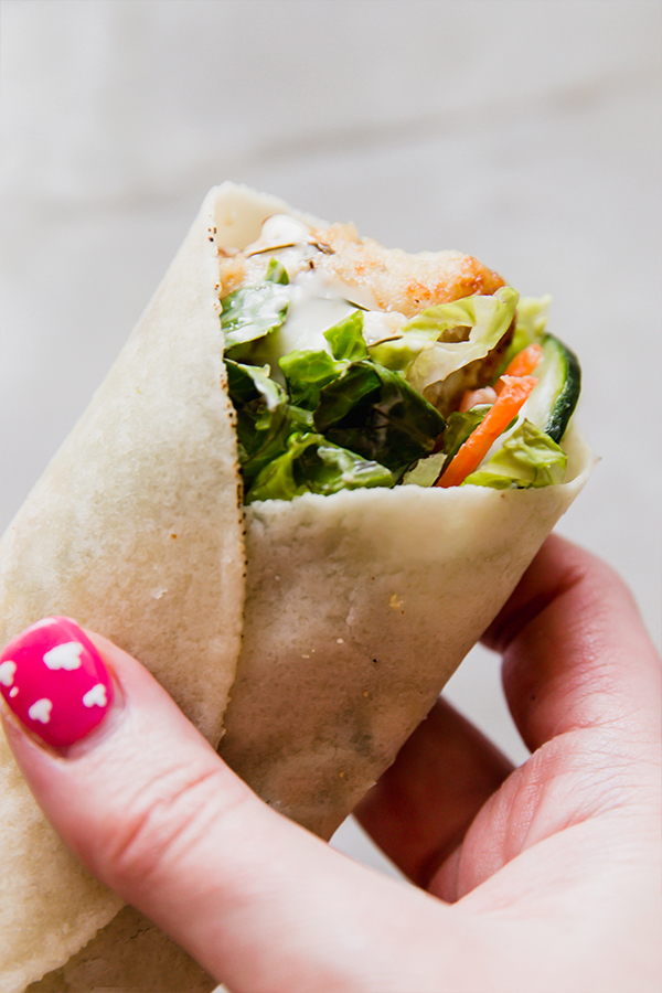 A crispy chicken snack wrap being held in a hand.