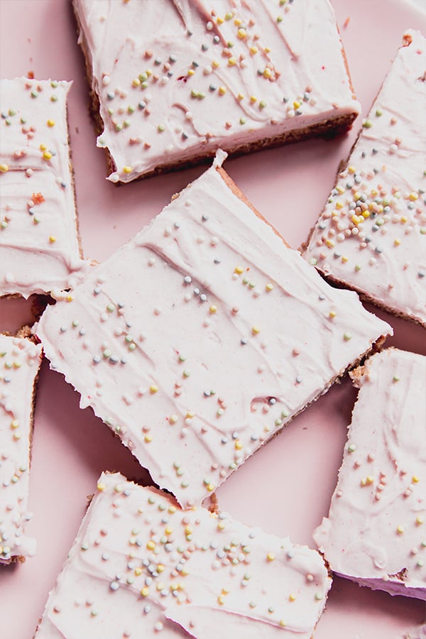 A few funfetti pink sugar cookie bars on a pink countertop.