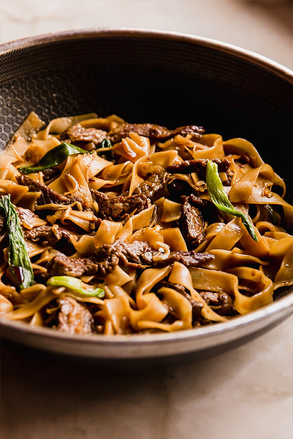 A wok filled with beef chow fun after cooking before being eaten.