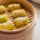 Several cabbage roll dumplings in a steamer.