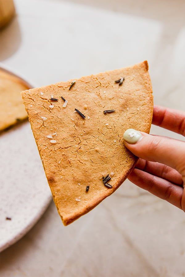 A piece of chickpea flatbread being held in a hand.