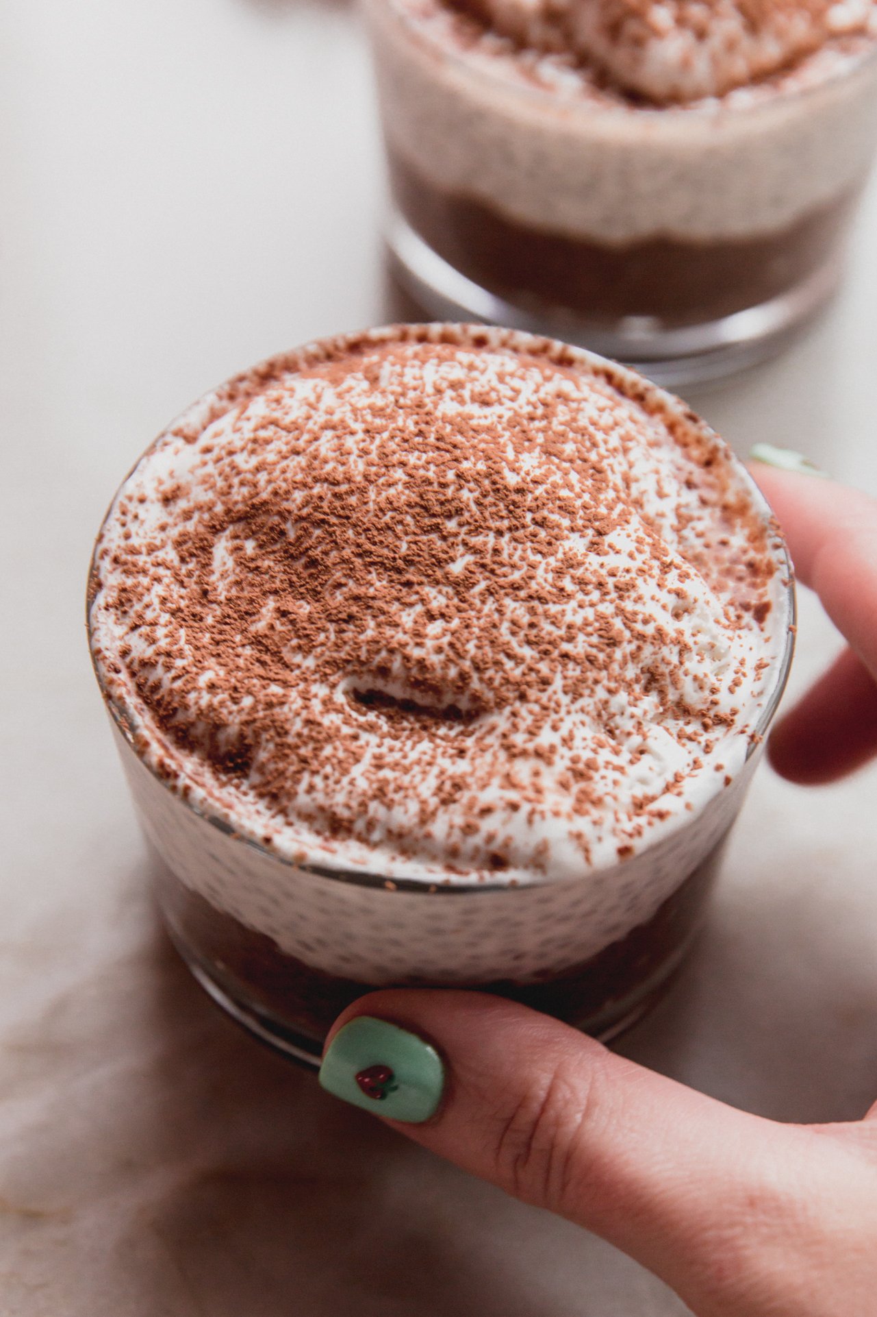 Tiramisu chia pudding in a glass being held. 
