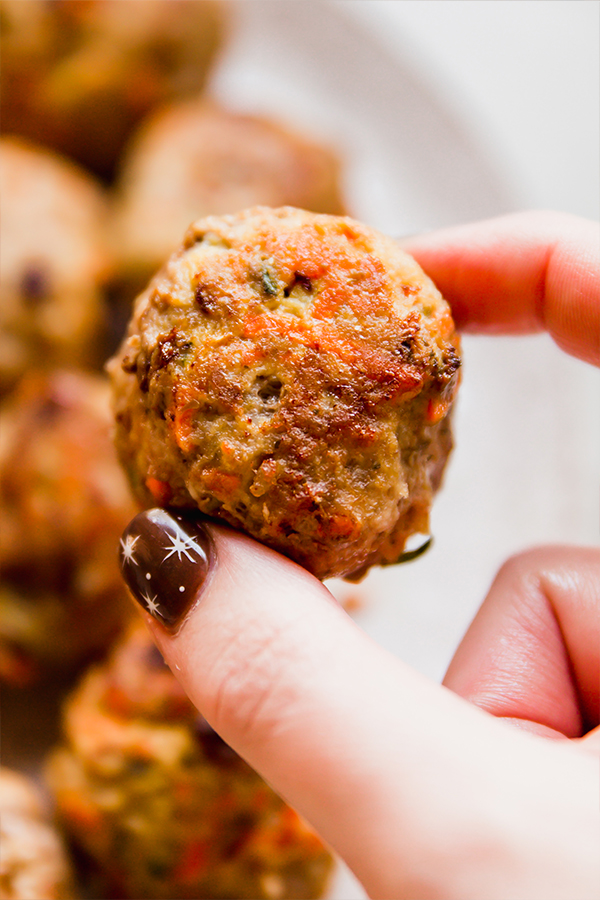 A hand holding a hidden veggie meatballs that is fully cooked.