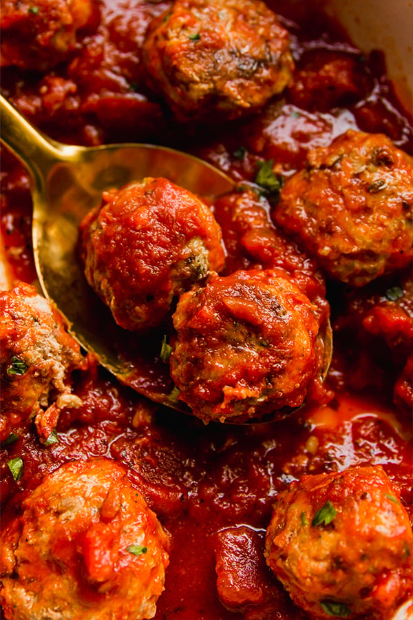 A pot of hidden veggie meatballs with a spoon serving a few meatballs.