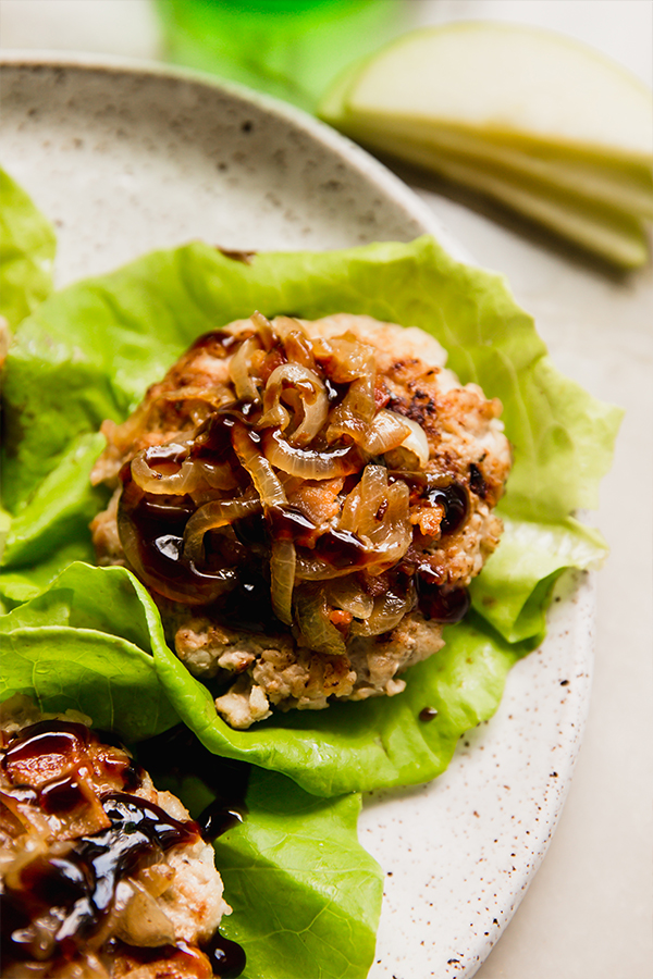 A plate filled with apple chicken burgers in lettuce wraps.