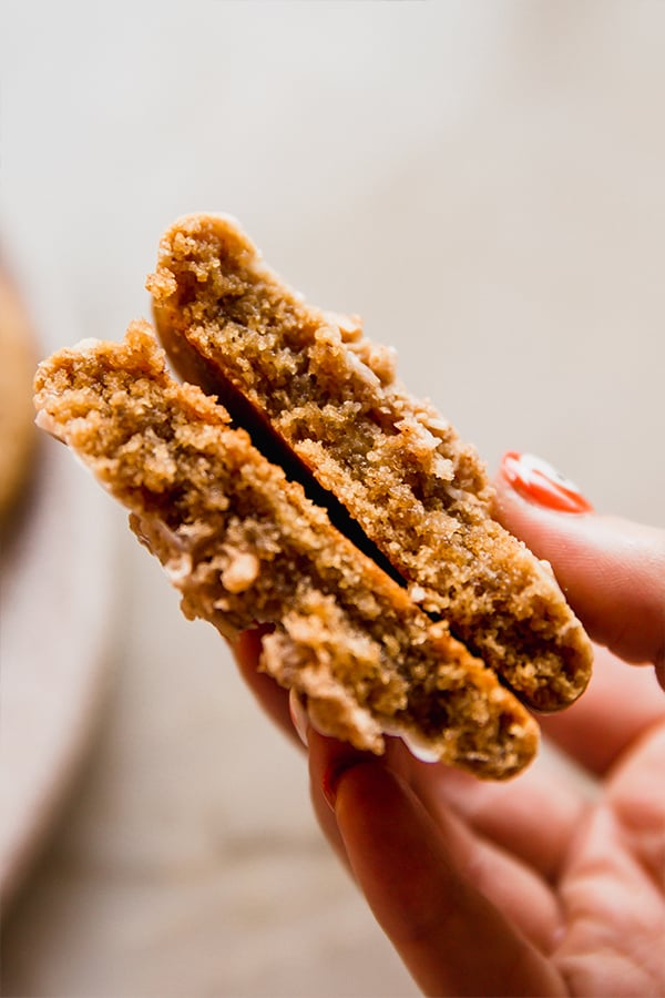 A coffee cake cookie broken in half and held in a hand.