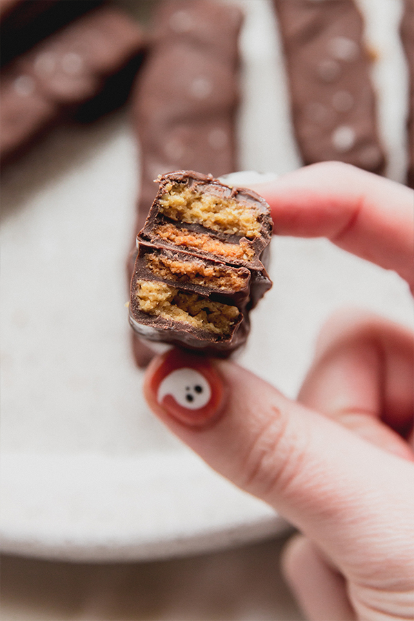 A kit kat bar folded in half being held in a hand.