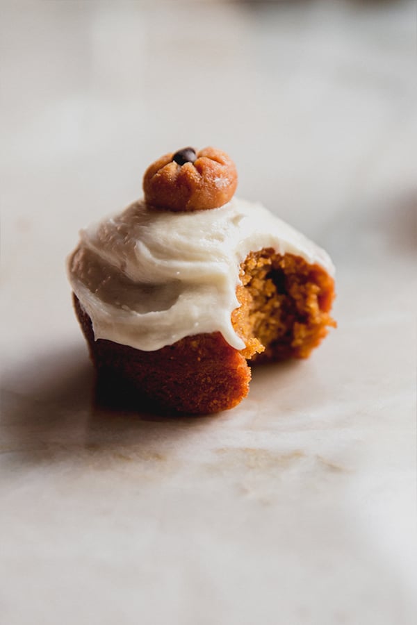 A pumpkin spice cupcake with a bite taken out of it.