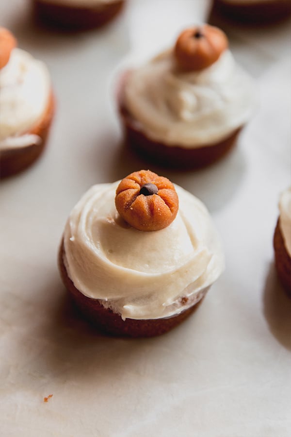 Pumpkin spice cupcakes sitting on a counter after being decorated.