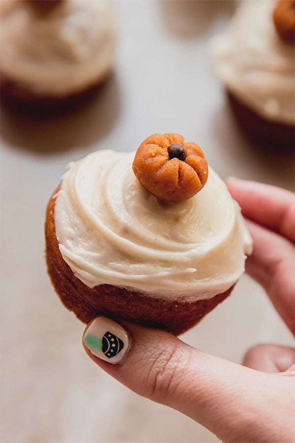 A pumpkin spice cupcake being held in a hand.