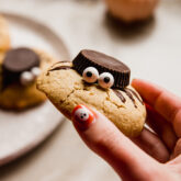 Person holding a cookie decorated to look like a spider.