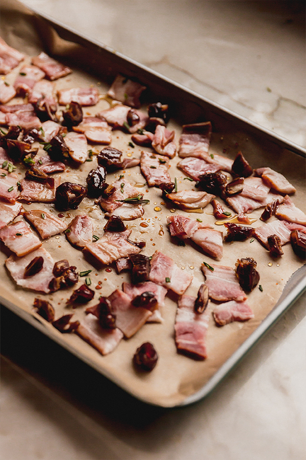 A baking sheet with bacon and dates in preparation for making the bacon date dip.