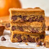 Three pumpkin cookie bars stacked on top of each other with a pumpkin in the background.