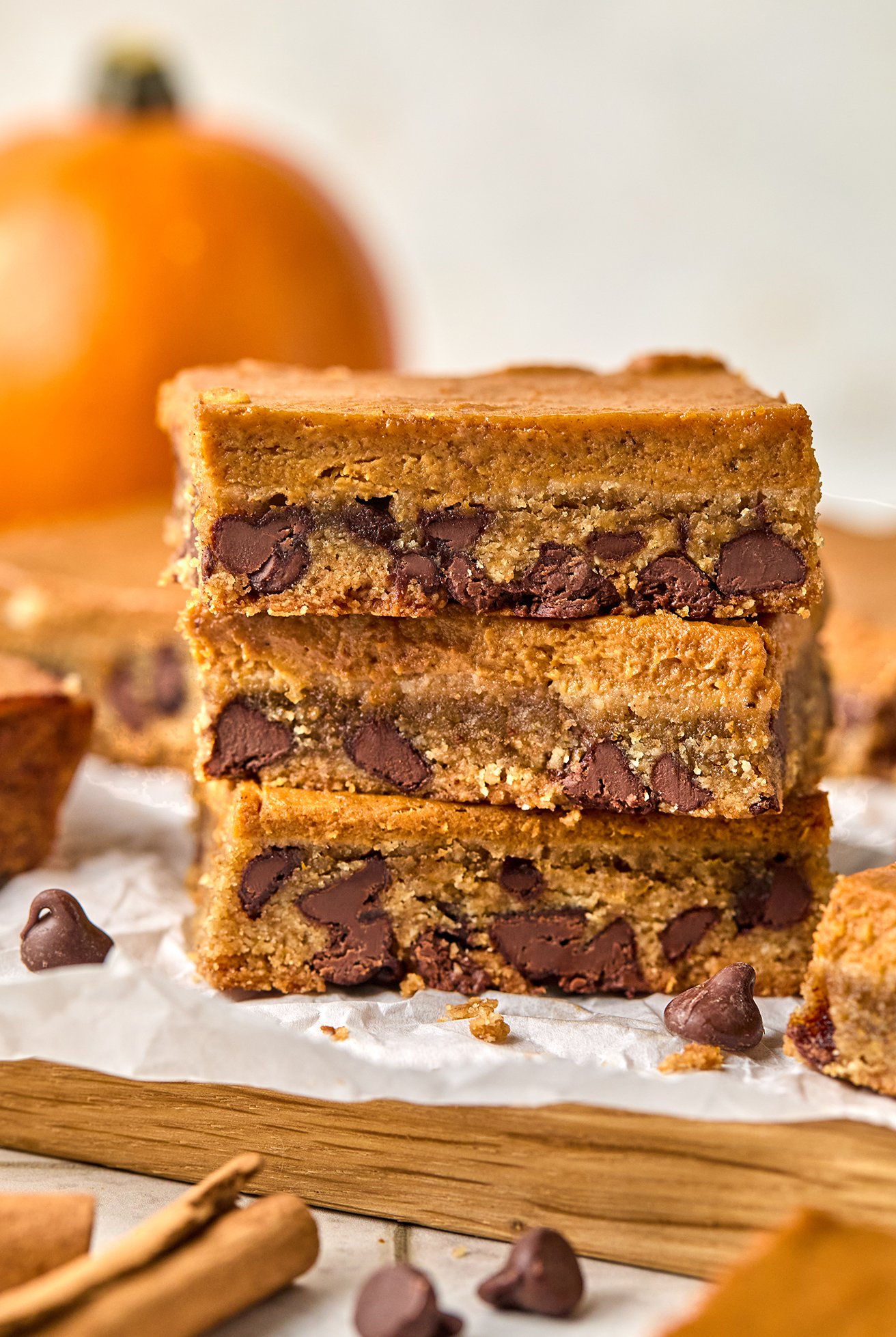 Three pumpkin chocolate chip cookie bars stacked on top of eachother. 