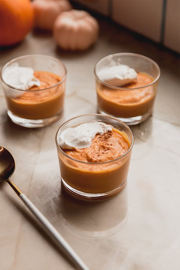 Three pumpkin cream cups sitting on a counter.