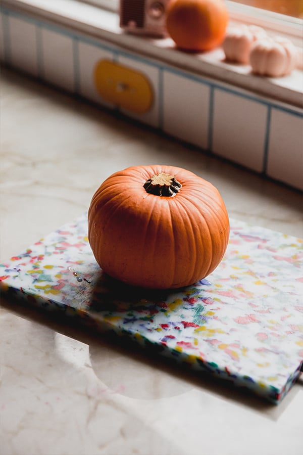 A pumpkin sitting on a counter before being roasted.