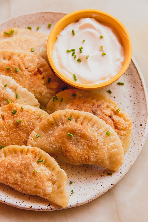 A plate filled with pumpkin ricotta pierogies with dipping sauce.