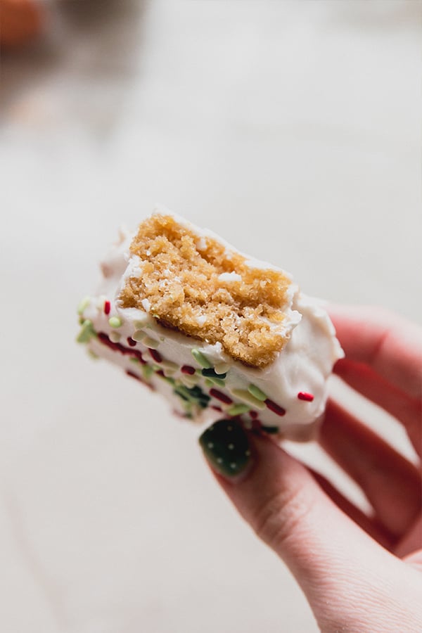 A copycat Little Debbie Christmas tree cake being held in a hand with a bite taken out of it.
