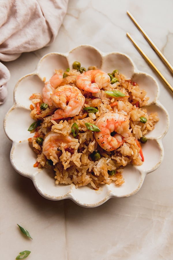 A plate filled with sheet pan shrimp fried rice sitting on a counter.