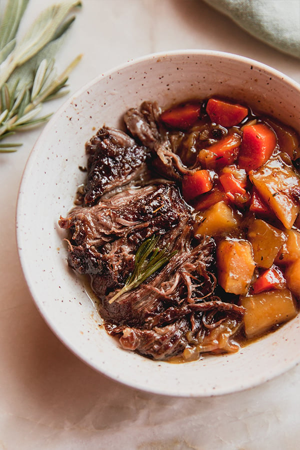 A bowl of apple cider braised pot roast with vegetables, ready to be enjoyed.