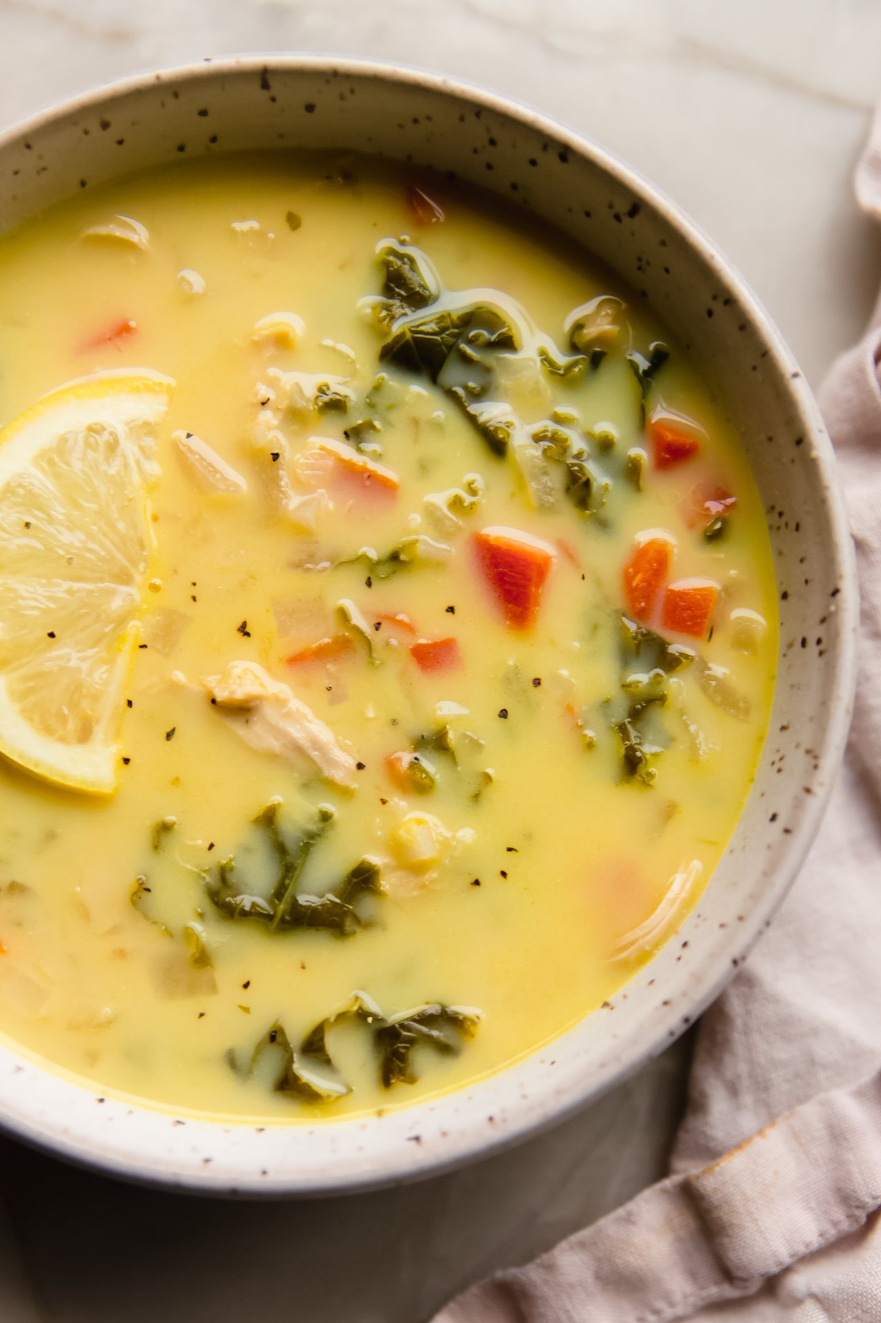 Greek lemon chicken soup in a bowl topped with a lemon wedge.