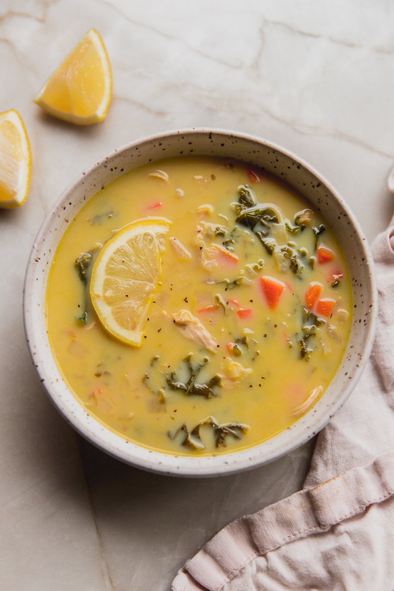 Greek lemon chicken soup in a bowl topped with a lemon wedge.