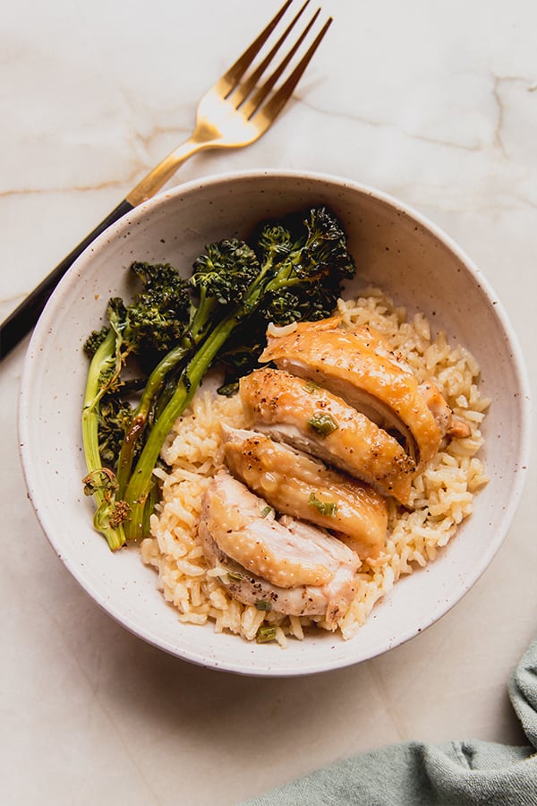 A bowl filled with rice cooker chicken, rice, and roasted broccolini.