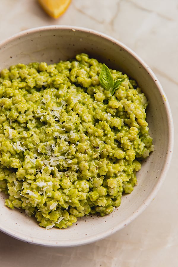A bowl of basil pesto stelline topped with cheese and olive oil.