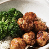 Honey garlic meatball on a dish with rice and broccoli.