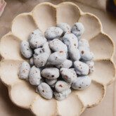 Blue chocolate covered almonds with brown speckles in a bowl.