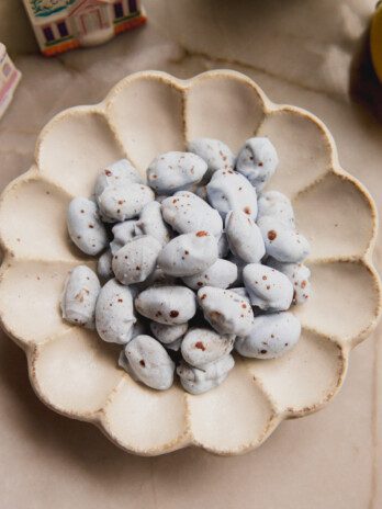 Blue chocolate covered almonds with brown speckles in a bowl.