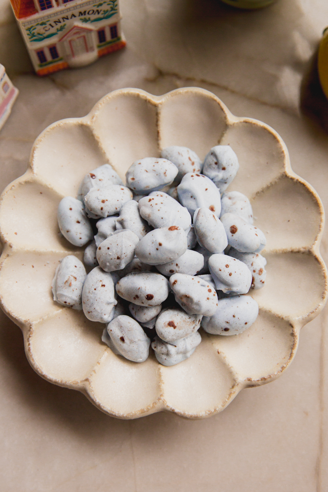 Blue chocolate covered almonds with brown speckles in a bowl.