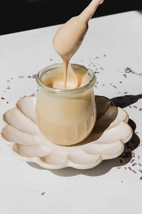 A whisk dripping homemade lavender whipped honey into a bowl of whipped honey.